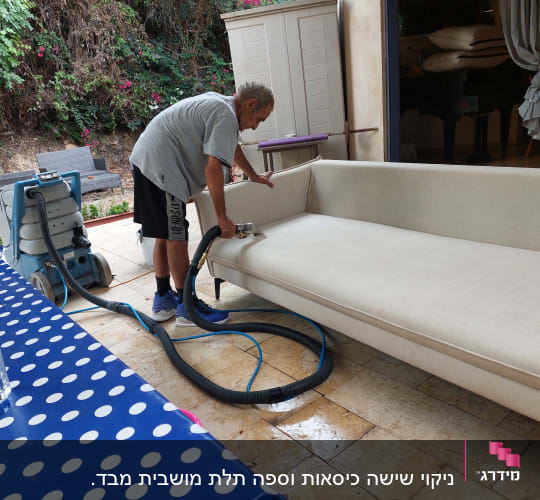 אדם מנקה ספה עם מכונת ניקוי מקצועית